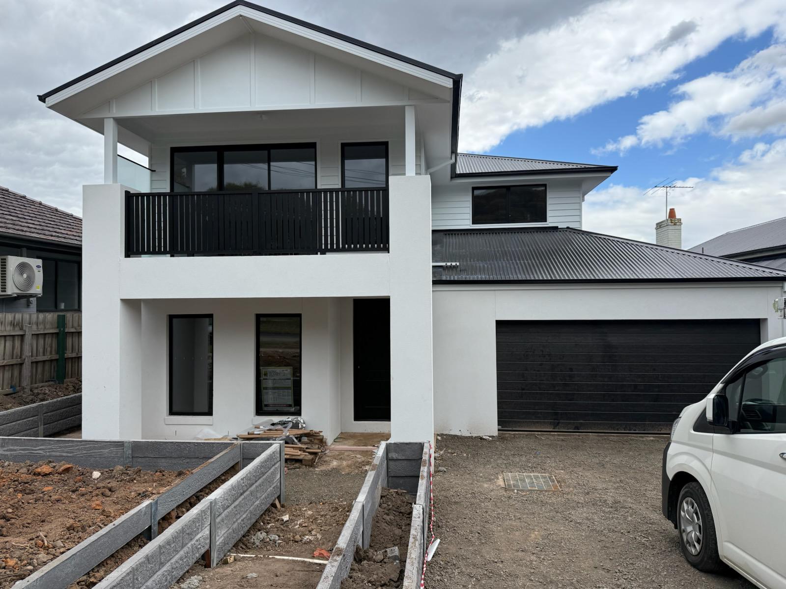 Two storey Melbourne home painted in white render with black trim and balcony