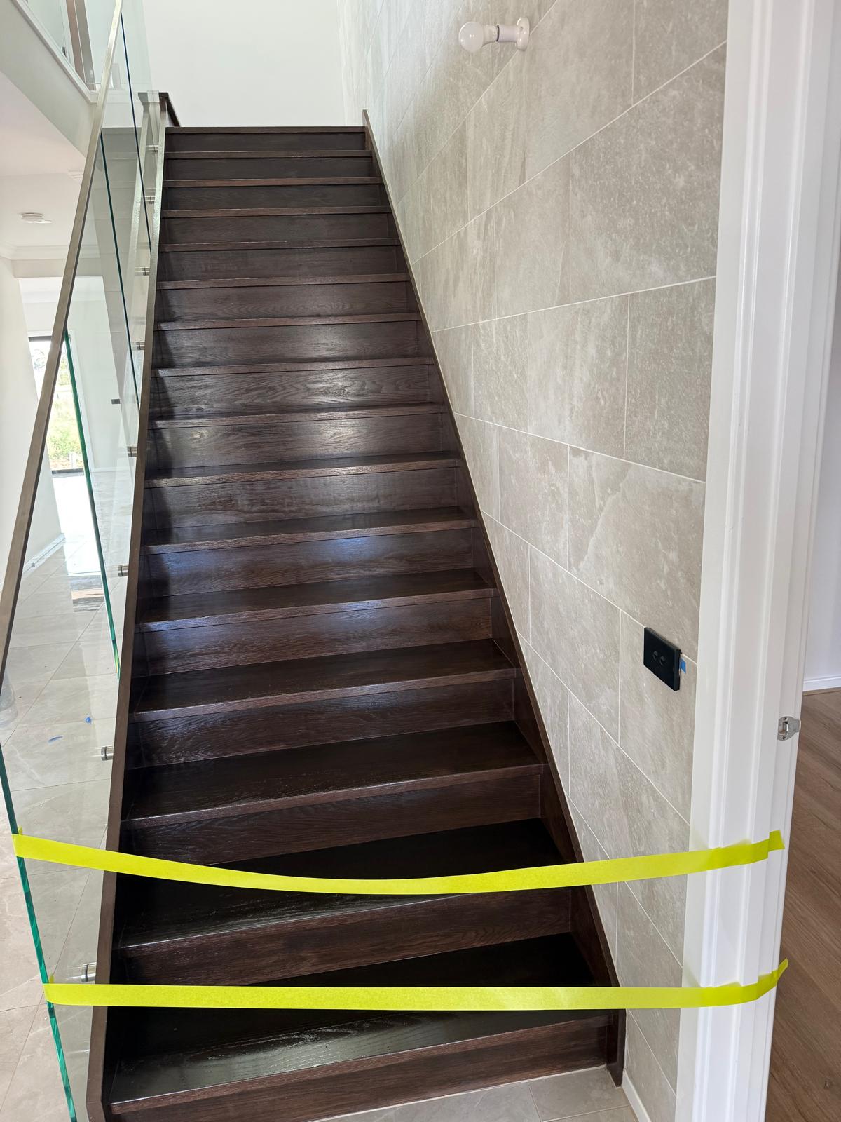 Dark stained timber staircase alongside a tiled feature wall